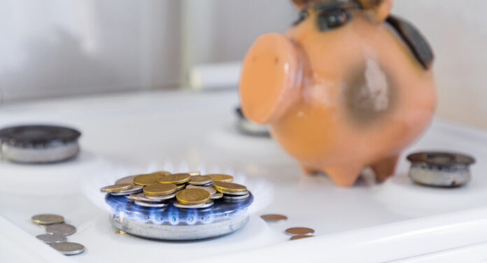 the concept of reasonable savings in utilities. cash coins on the gas burner on the background of the piggy Bank